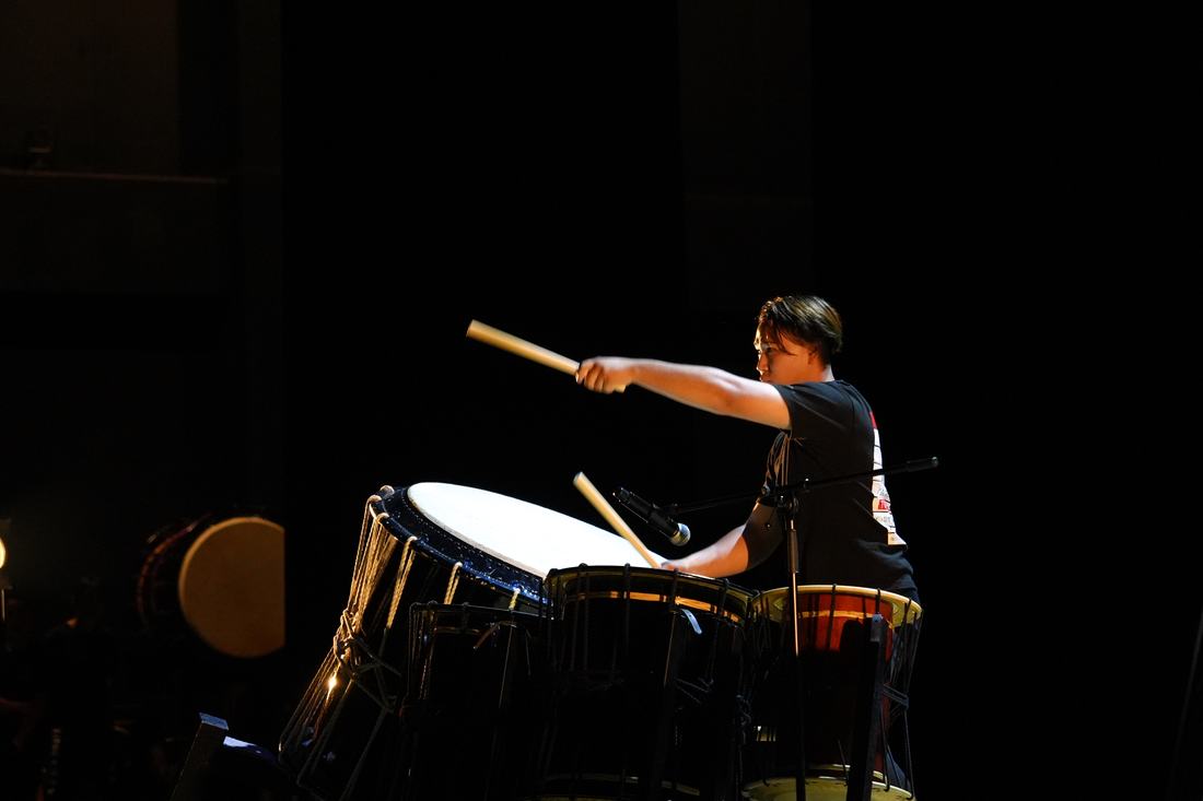 スポットライトの中で締太鼓を打つ演者